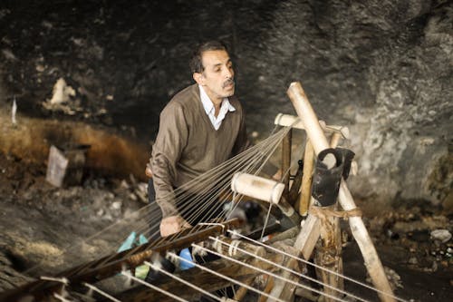 A Man Working on a Wooden Knitting Machine