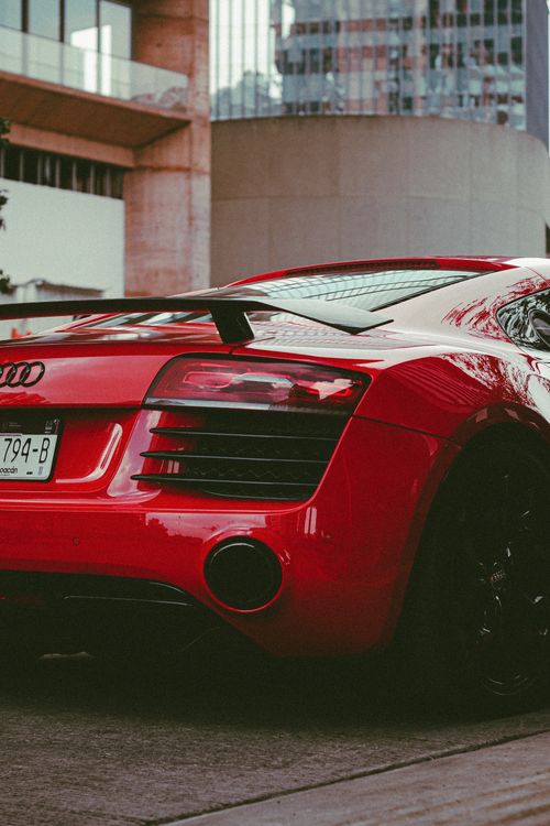 Free Captivating rear view of a sleek red sports car parked outdoors in a modern urban environment. Stock Photo