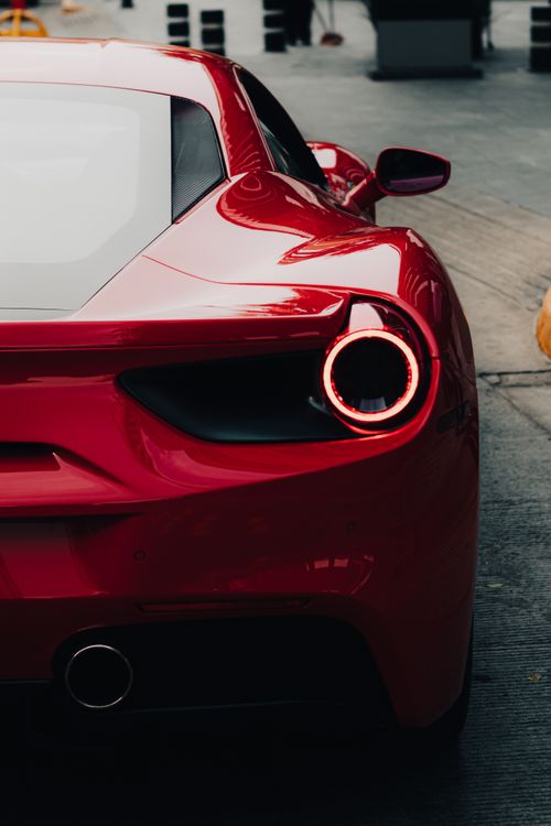 Free Sleek red Ferrari 458 viewed from the back on a city street, showcasing luxury and speed. Stock Photo