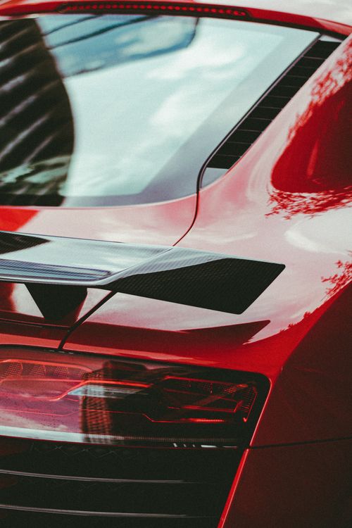 Free Detailed view of a modern red sportscar's aerodynamic rear design, emphasizing speed. Stock Photo