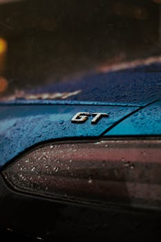 A detailed view of a GT sportscar with raindrops on the surface. Captured in a rainy setting.