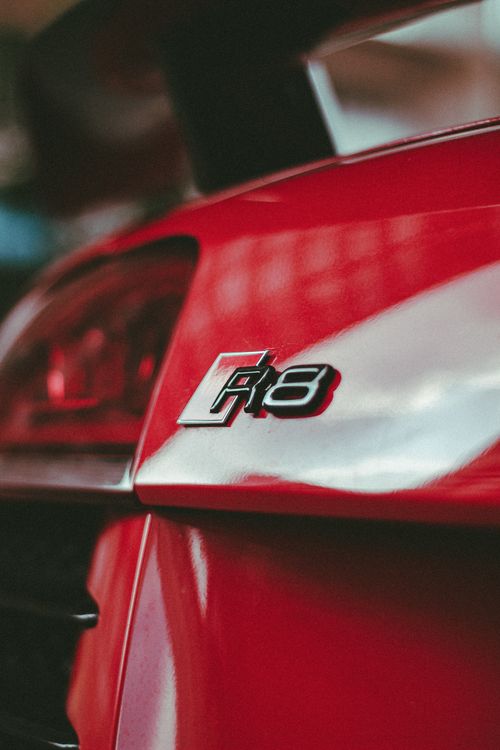 Free A detailed close-up of a red sports car featuring the R8 emblem, highlighting the sleek design. Stock Photo