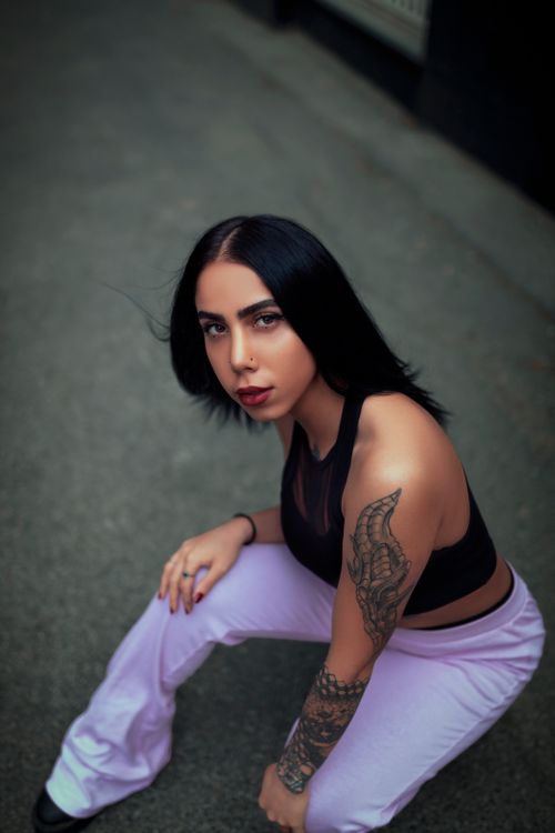 Free Fashion portrait of a woman with an arm tattoo in a crop top, taken outdoors from a high angle. Stock Photo