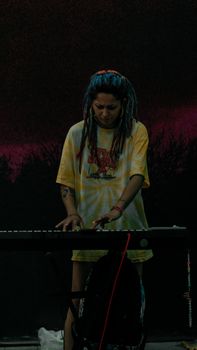 A female street musician with dreadlocks plays keyboard in Istanbul at night.