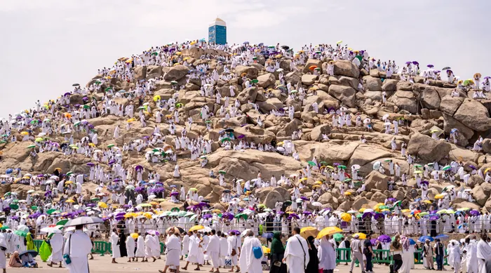 Pilgrims in white gathered on the rocks of Jabal al-Rahmah at Arafat during Hajj