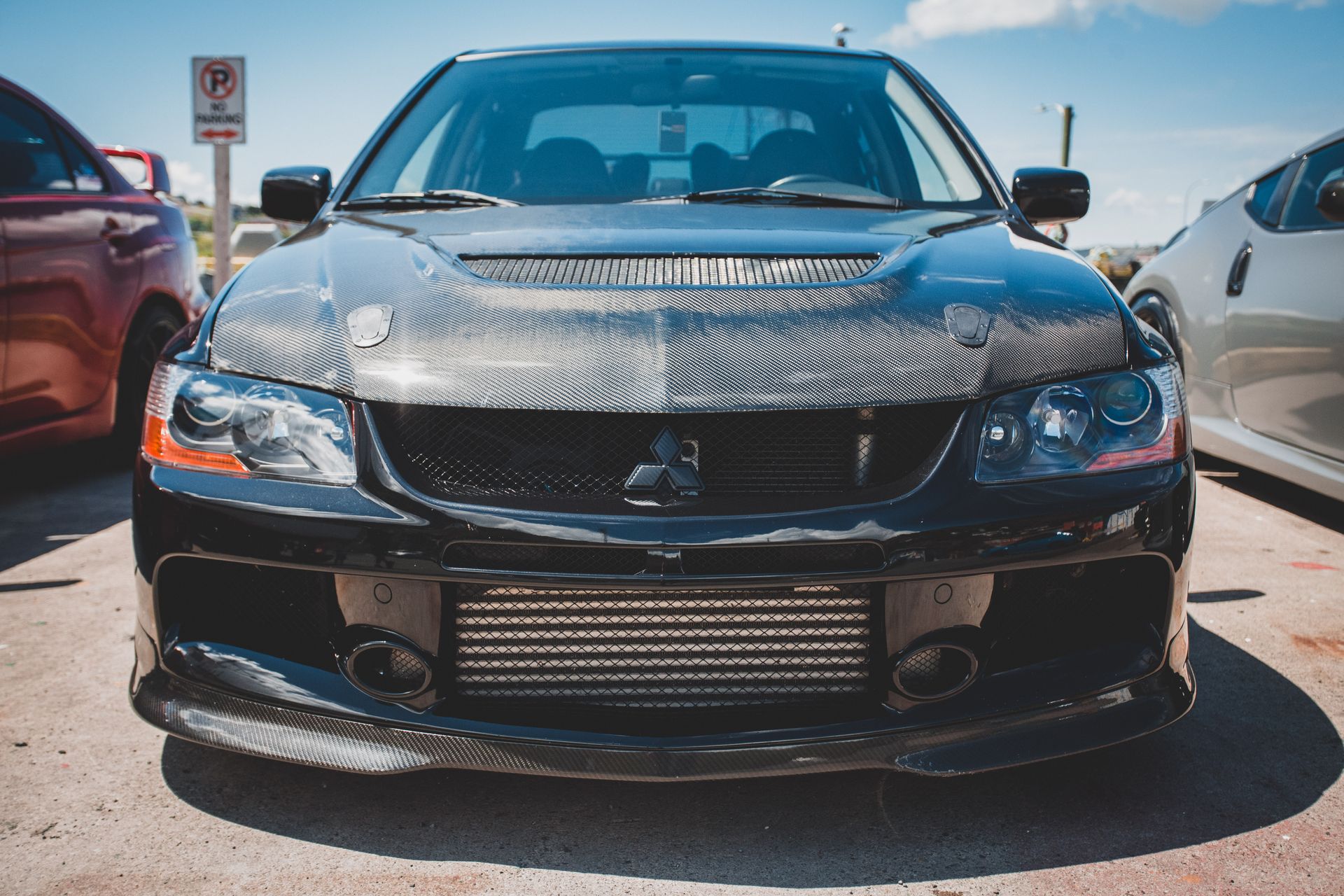 Front view of a black Mitsubishi Lancer Evolution parked outdoors in daylight.