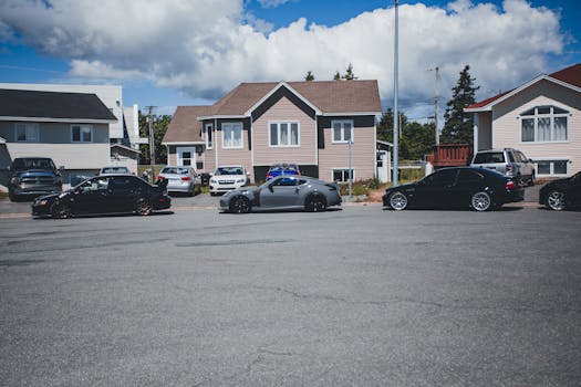 Sunny neighborhood street with modern homes and parked vehicles on a bright day.
