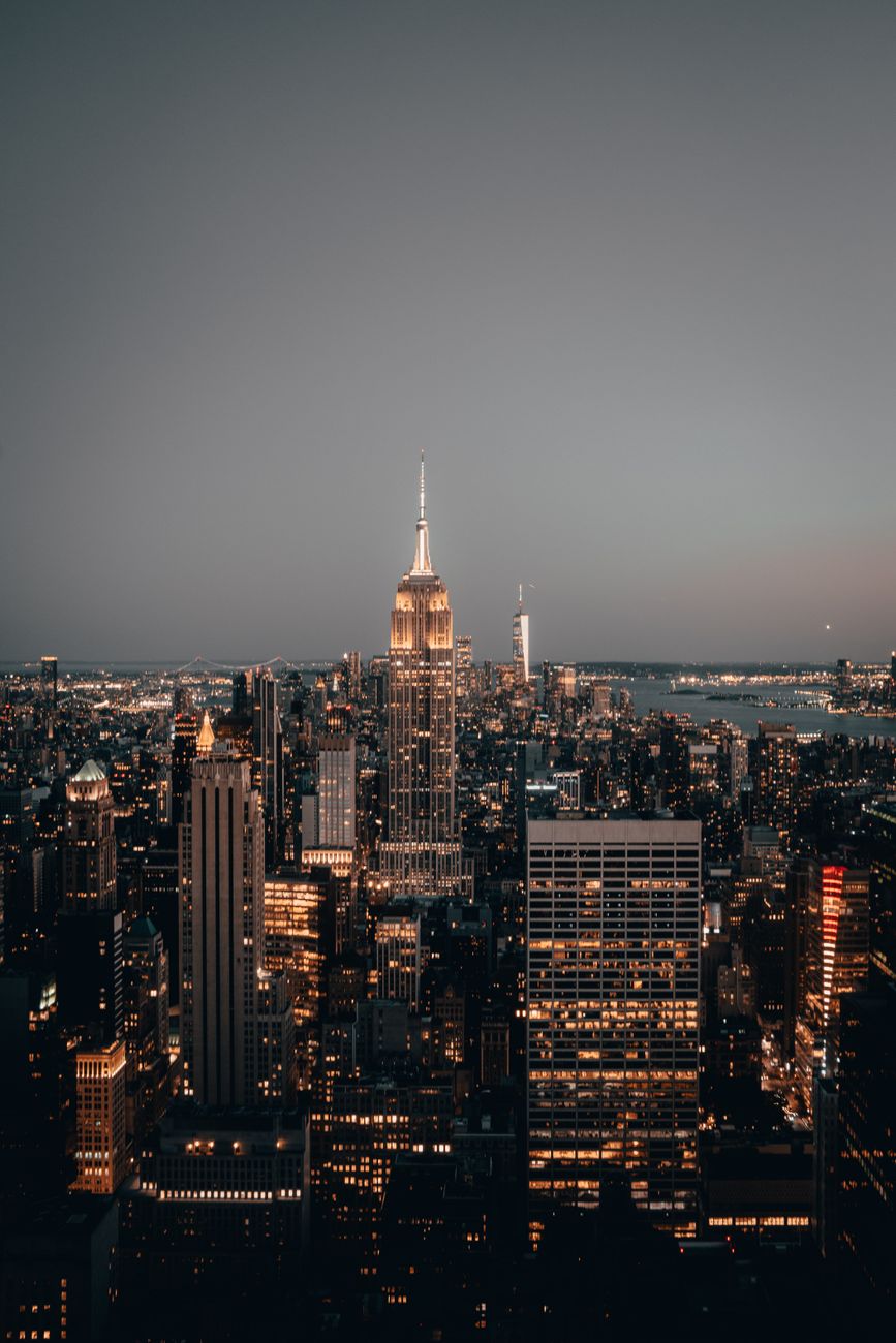 Majestic view of New York City skyline featuring the illuminated Empire State Building at dusk.