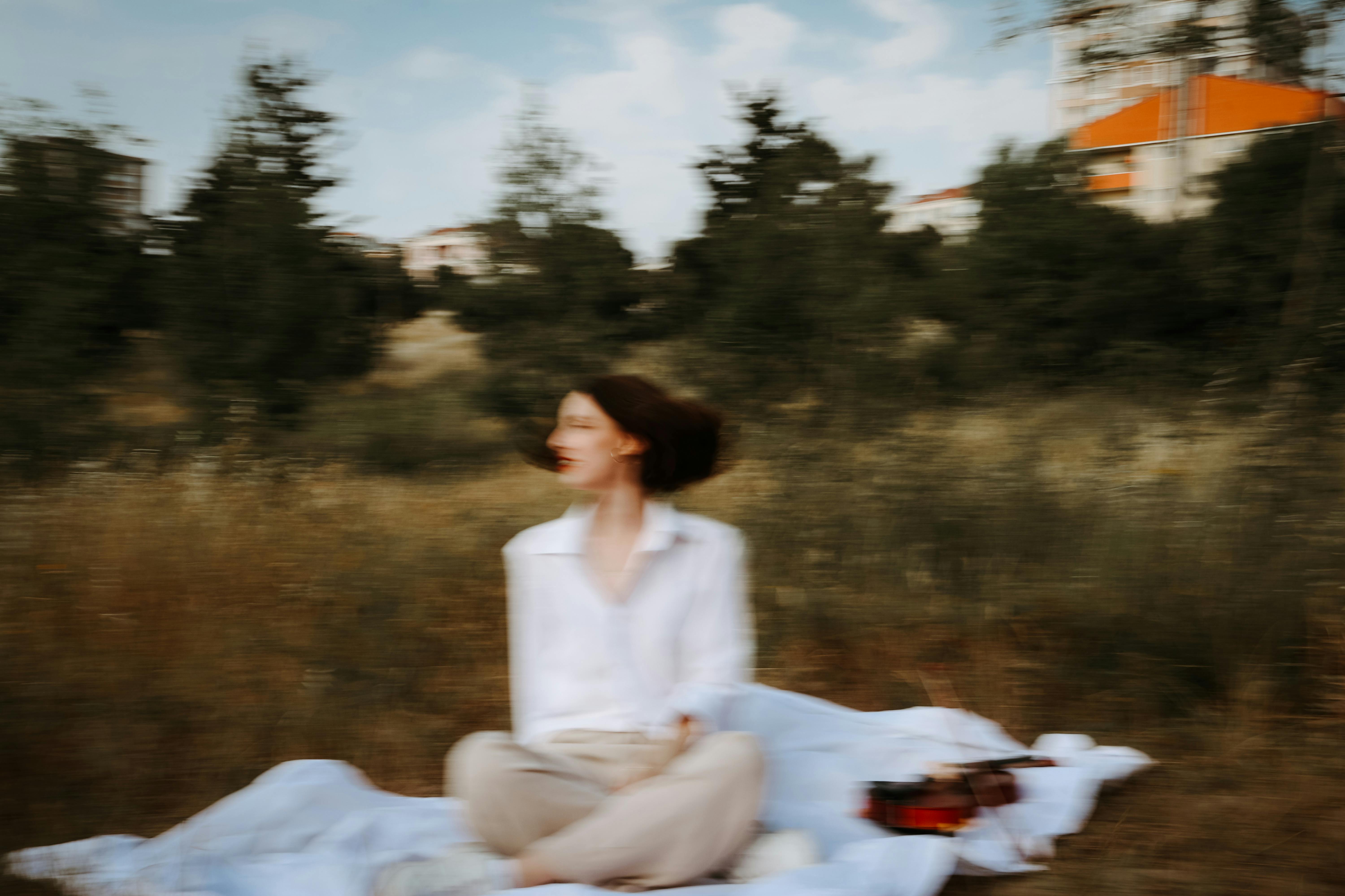 Artistic blurred image of a woman sitting outdoors on a sunny day.