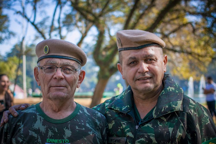 Portrait Of Two Veterans In Military Clothing And Tree In Background