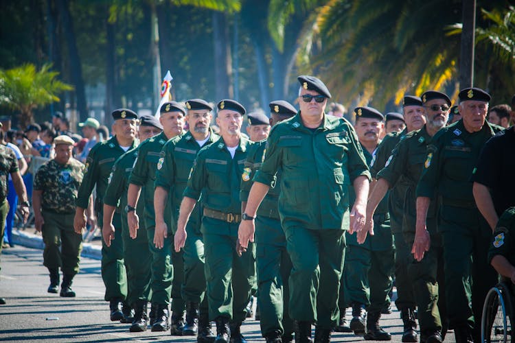 Photo Of Military Veterans In Green Uniforms Marching On The Street