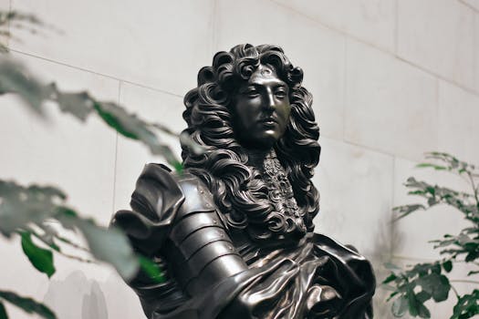 Elegant bronze sculpture of a historical figure with flowing hair and armor, embraced by plants.
