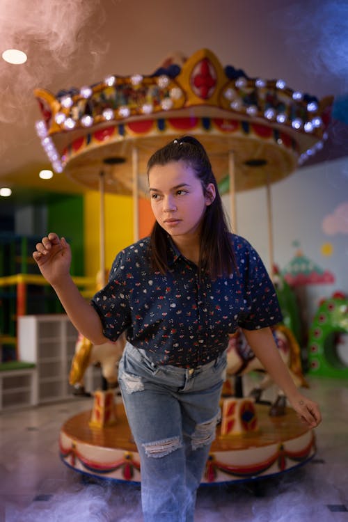 Woman in Spotted Shirt against Carousel
