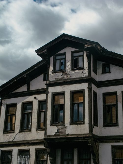 Free A decaying, derelict building with broken windows and a cloudy sky backdrop, exuding a vintage charm. Stock Photo