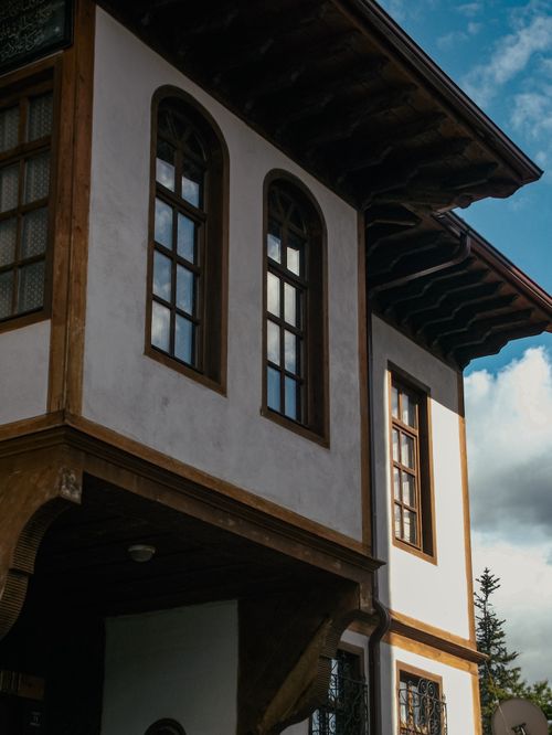 Free Close-up view of a traditional building facade with wooden details and arched windows against a blue sky. Stock Photo