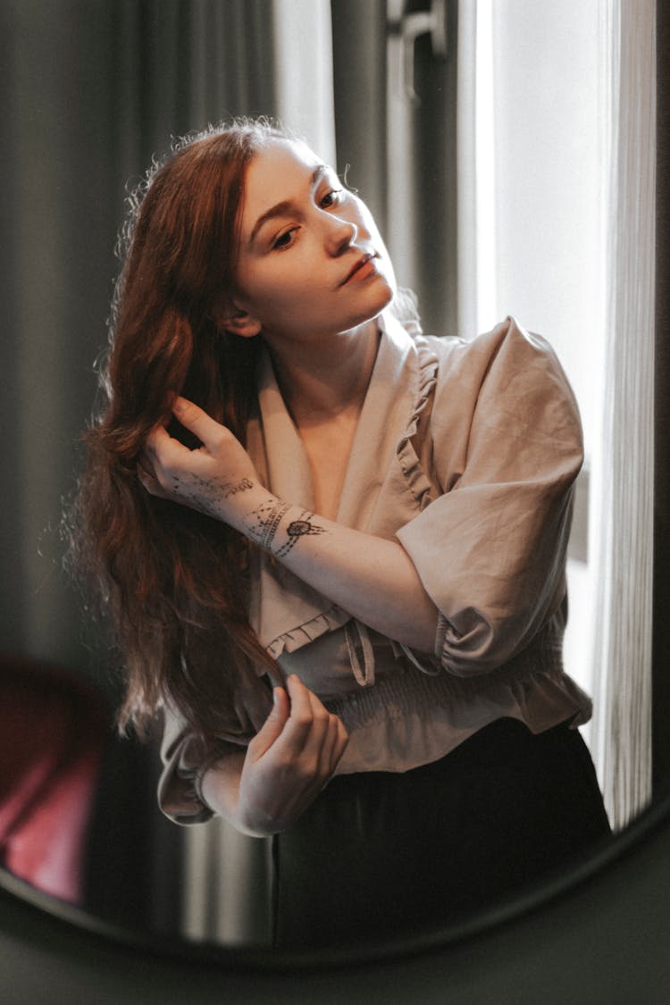 Woman Touching Her Hair In Front Of A Mirror