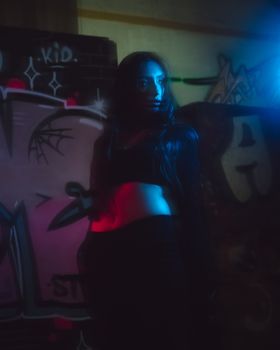 Striking portrait of a woman in urban graffiti background with moody lighting.