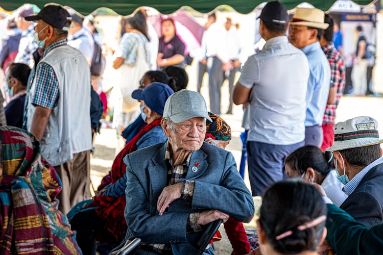 An Elderly Man Sitting Among Crowd Of People