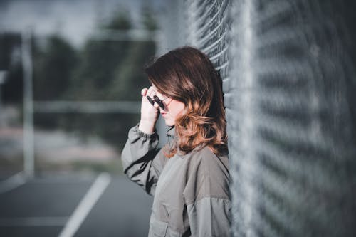 Foto profissional grátis de apoiando, mulher, óculos de sol