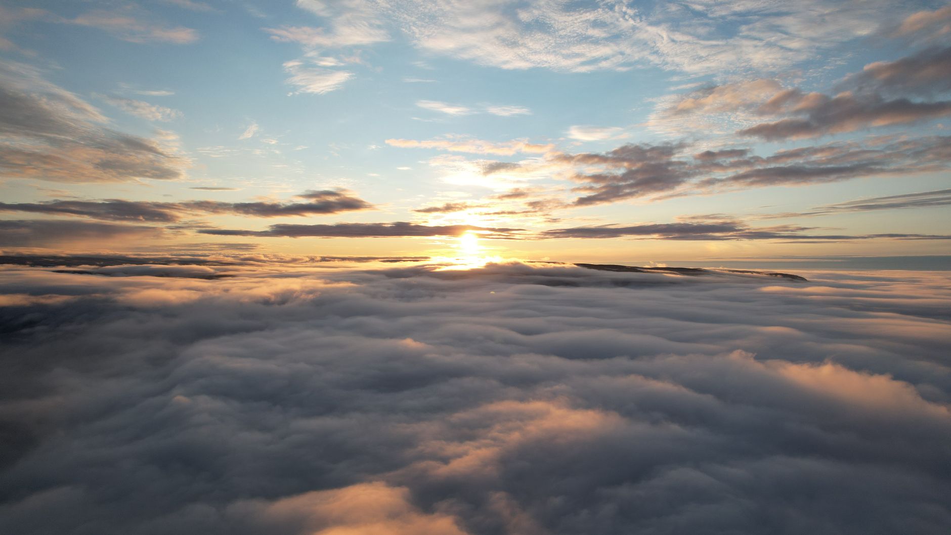 Captivating sunrise view over a sea of clouds, showcasing a serene golden hour above Kangiqsujuaq, Canada.