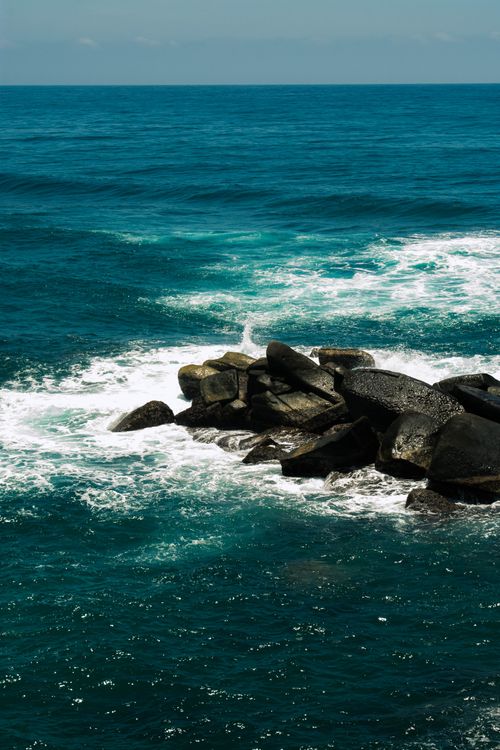 Free Captivating vertical shot of ocean waves crashing on a rocky shoreline, showcasing nature's power and beauty. Stock Photo