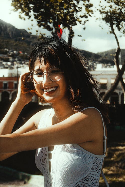 Woman in White Tank Top Wearing Eyeglasses Smiling