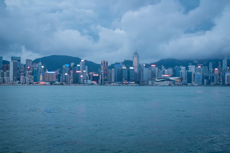 City Skyline Across Body Of Water Under White Clouds