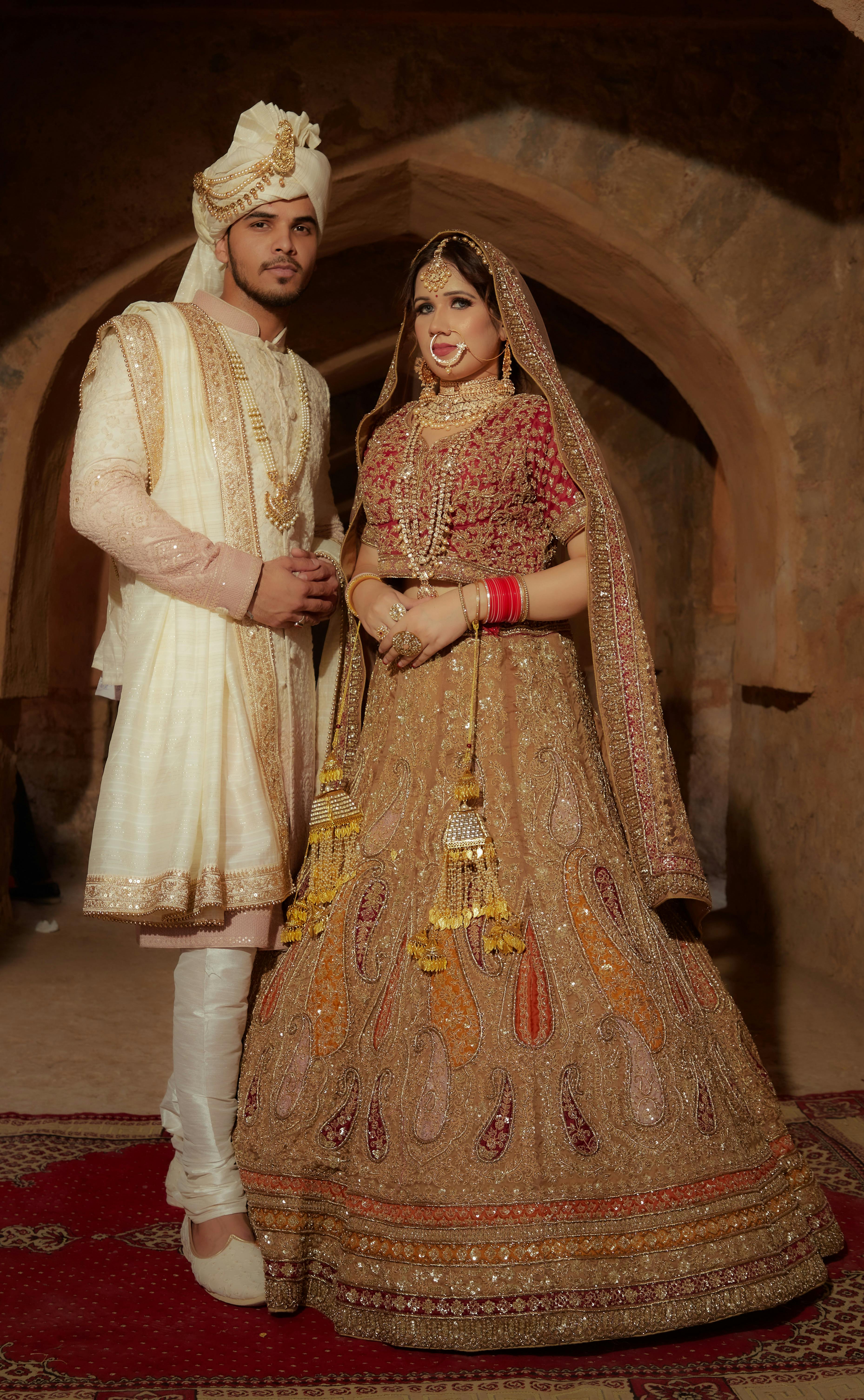 Elegant portrait of an Indian bride and groom in traditional attire, captured indoors with rich details.