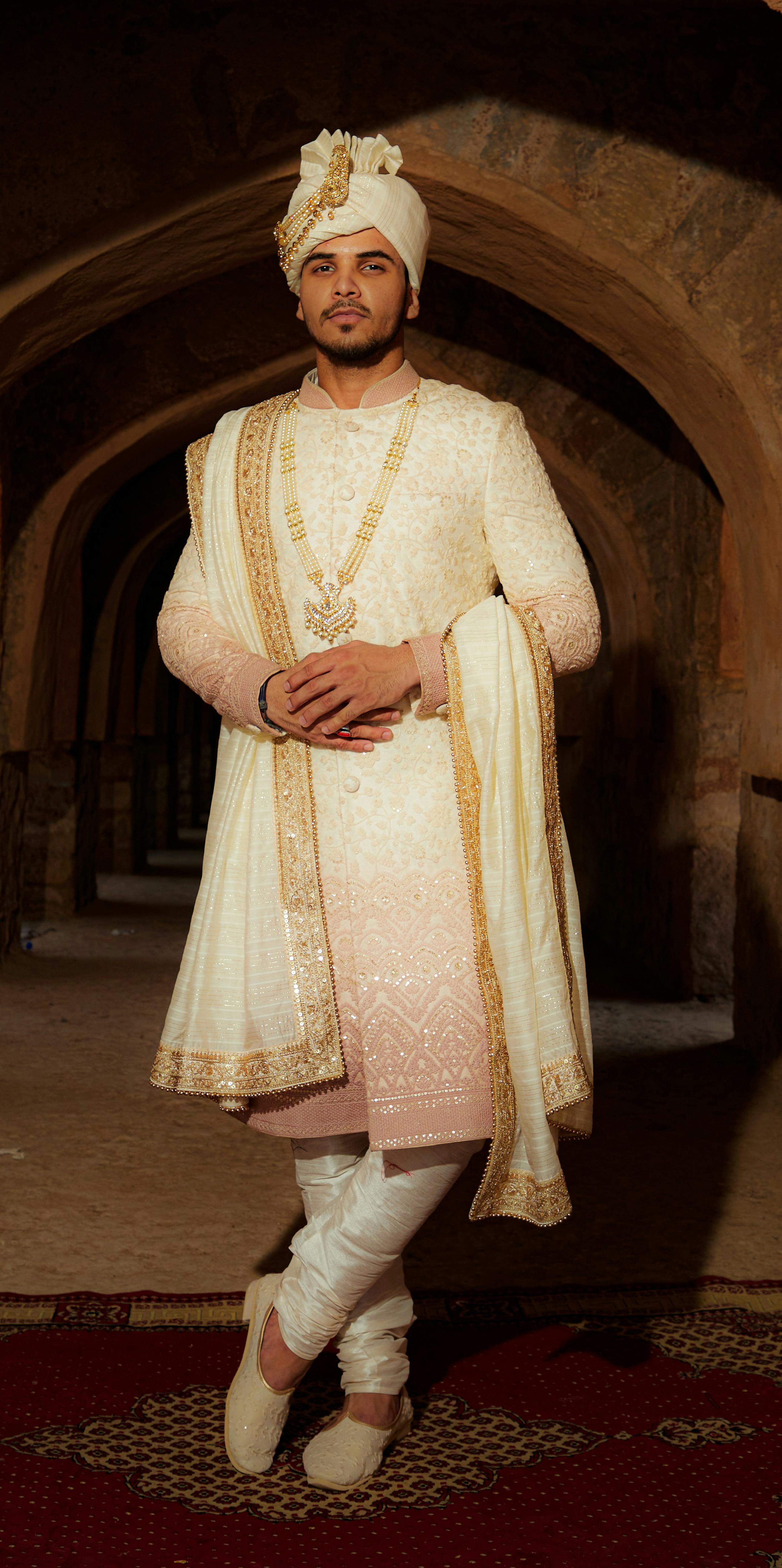 man wearing traditional white clothing posing in a cellar with arches