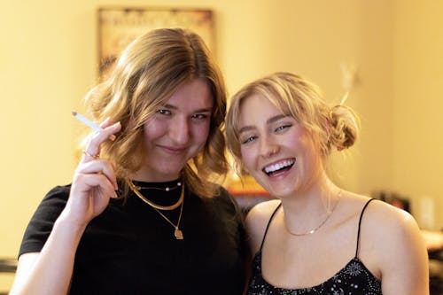 Blond Women Wearing Black Tops and Gold Jewellery Posing Together in a Yellow Interior