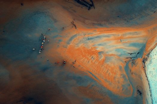 Stunning aerial photo showcasing a vibrant beach landscape with colorful sands and small figures.