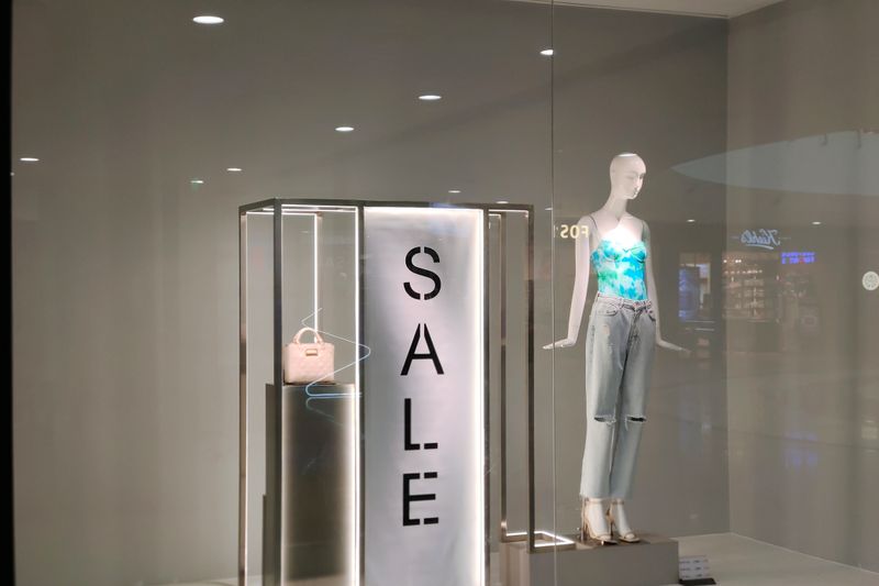 Stylish window display featuring sale sign and fashionable mannequin in trendy outfit.