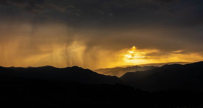 Breathtaking golden hour sky over the silhouette of mountains in Dumești, Romania.