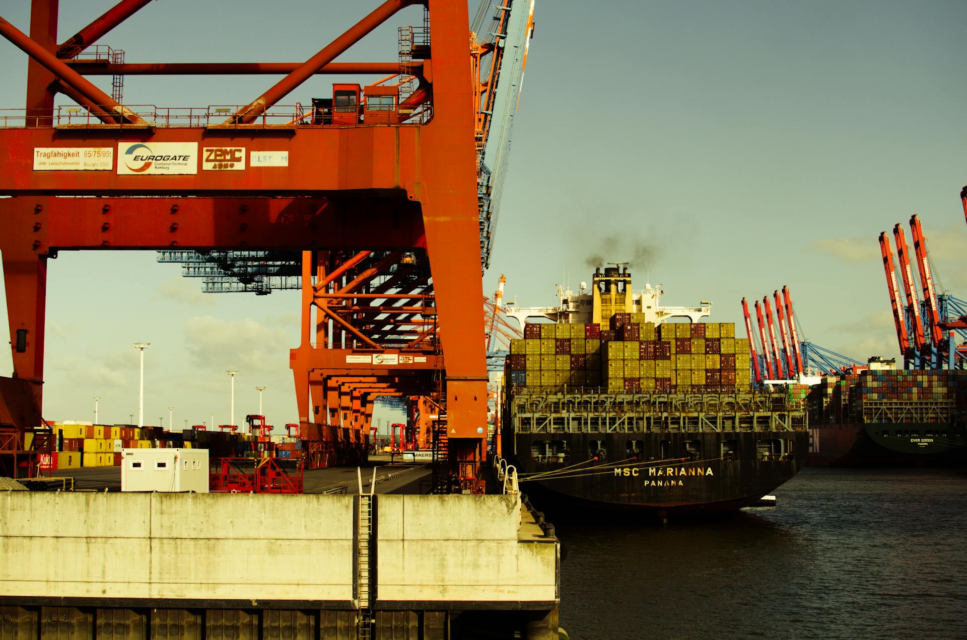 A container ship unloading cargo at a busy industrial port with cranes ready for transport.