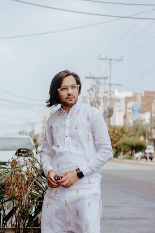 Free A man with long hair and glasses in a traditional kurta on a city street. Stock Photo