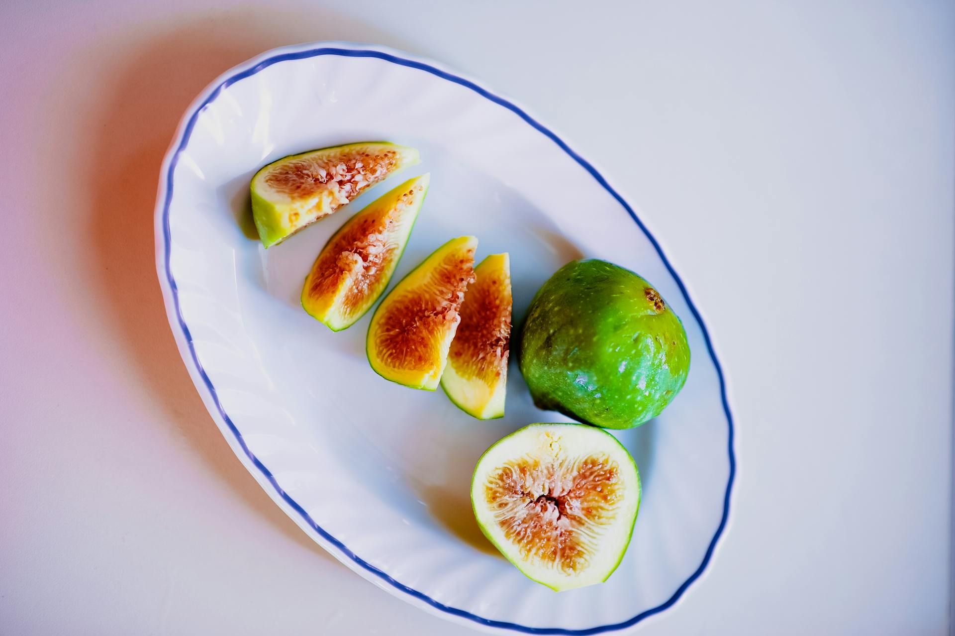 Overhead view of sliced Cilento white figs on a ceramic plate, showcasing freshness and natural colors.