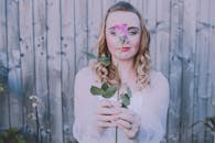 木栅栏前，一名手持粉红色玫瑰的金发女子，在柔和温暖的色调中留下肖像