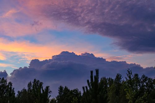 Free Beautiful twilight sky with dramatic clouds and silhouette trees in the foreground. Stock Photo