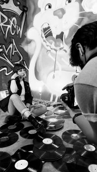 Black and white studio photoshoot with a woman among vinyl records.