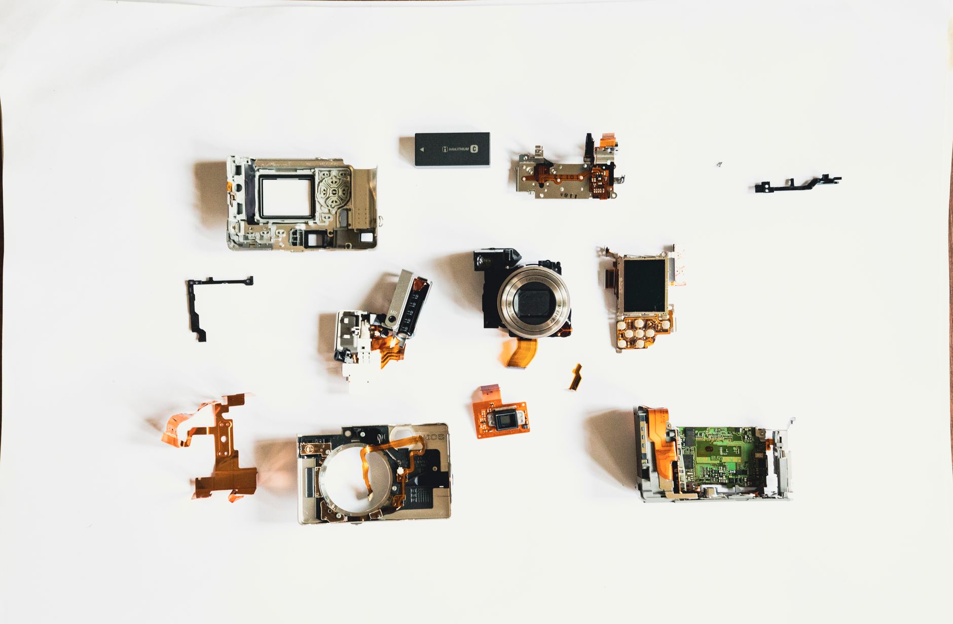 Close-up of disassembled camera components arranged on a white surface.