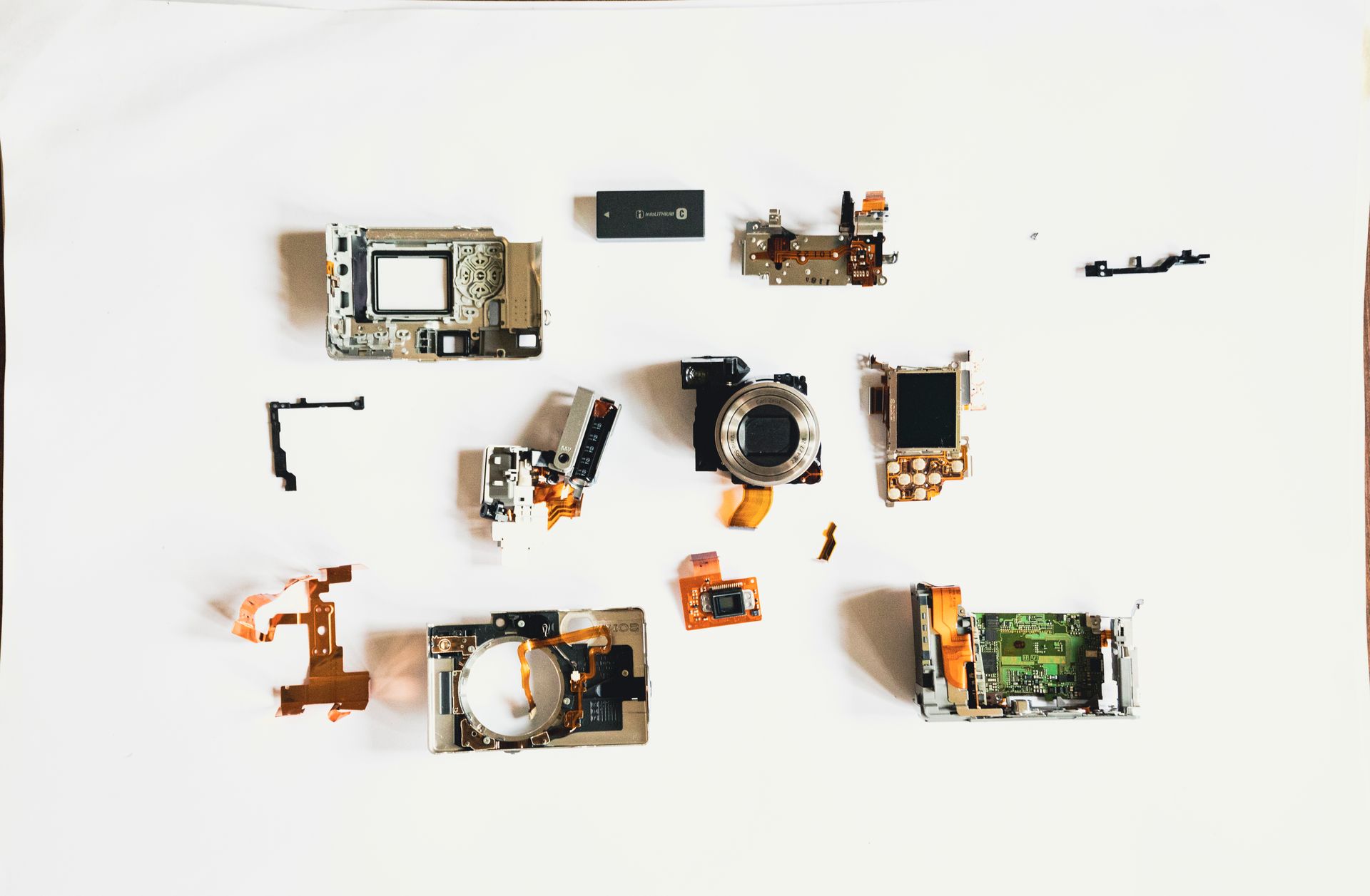 Close-up of disassembled camera components arranged on a white surface.