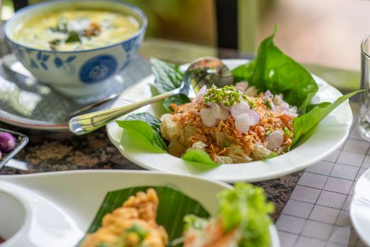 Close-up of a vibrant Asian salad with fresh greens, onions, and a creamy soup.