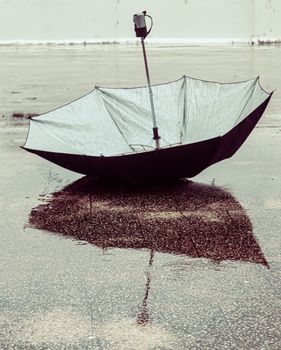 An upside down umbrella reflecting on a wet street in Ajmer, India, showing an artistic view of rainy weather.