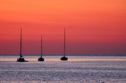 Silhouette of Three Sailing Ships on the Ocean during Sunset