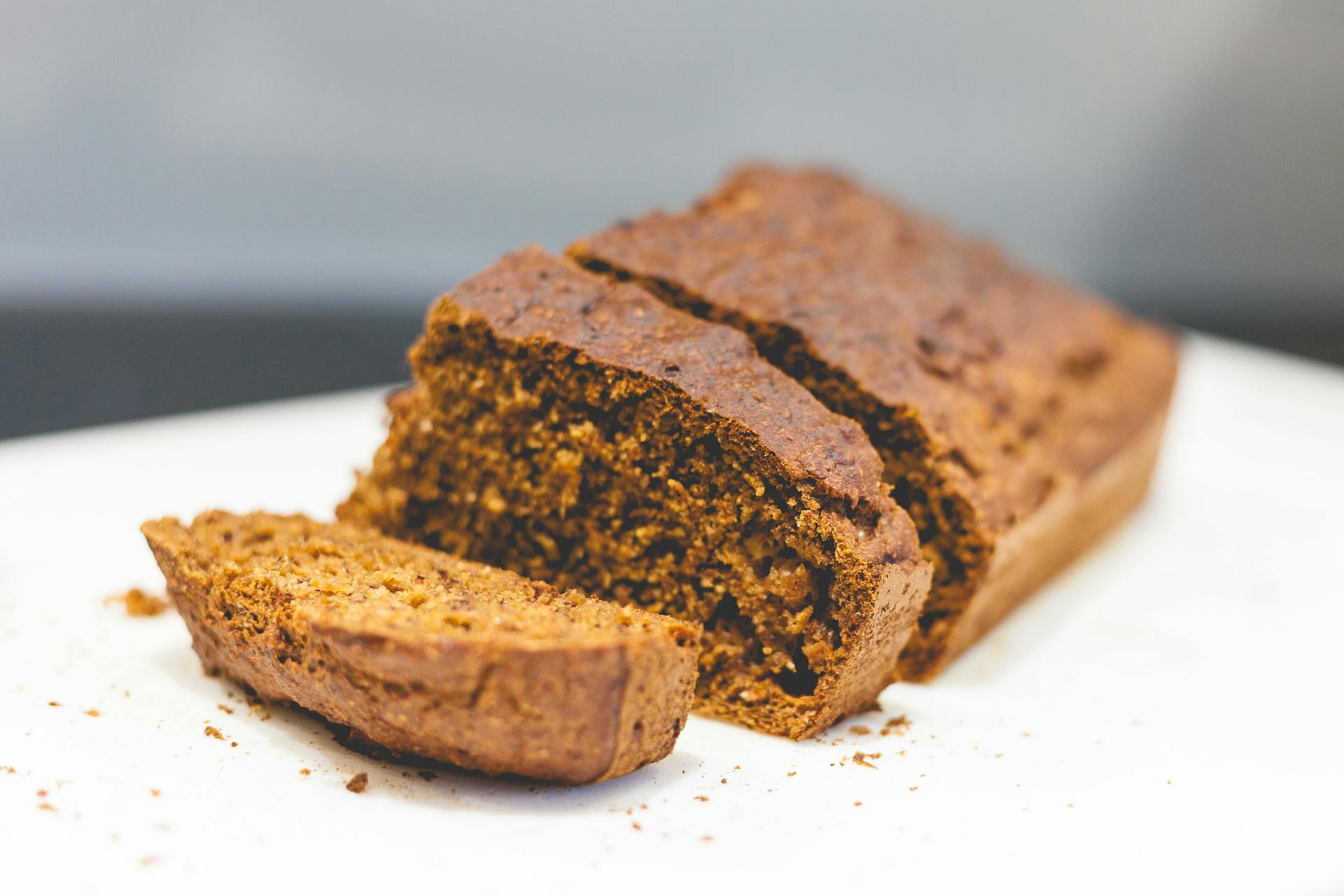 Delicious homemade banana bread sliced on a white surface with a rustic texture.
