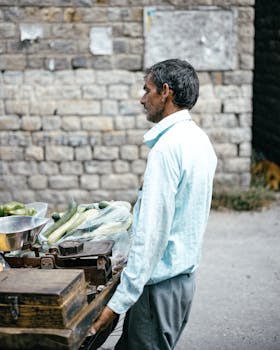 A man selling fresh vegetables from a cart on a street in Kullu, India.