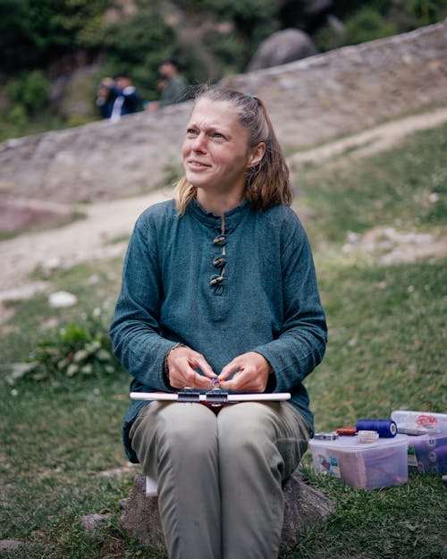 A Woman in Blue Long Sleeve Shirt Sitting on Gray Rock