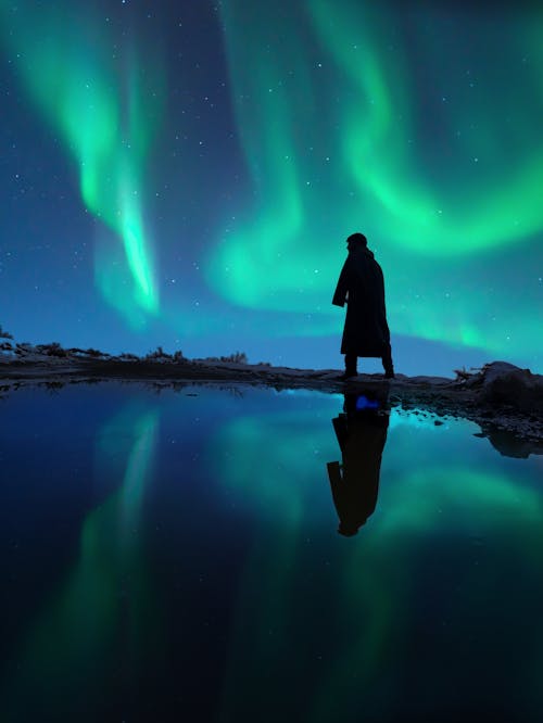 Silhouette of Person Walking in Nature in Northern Lights