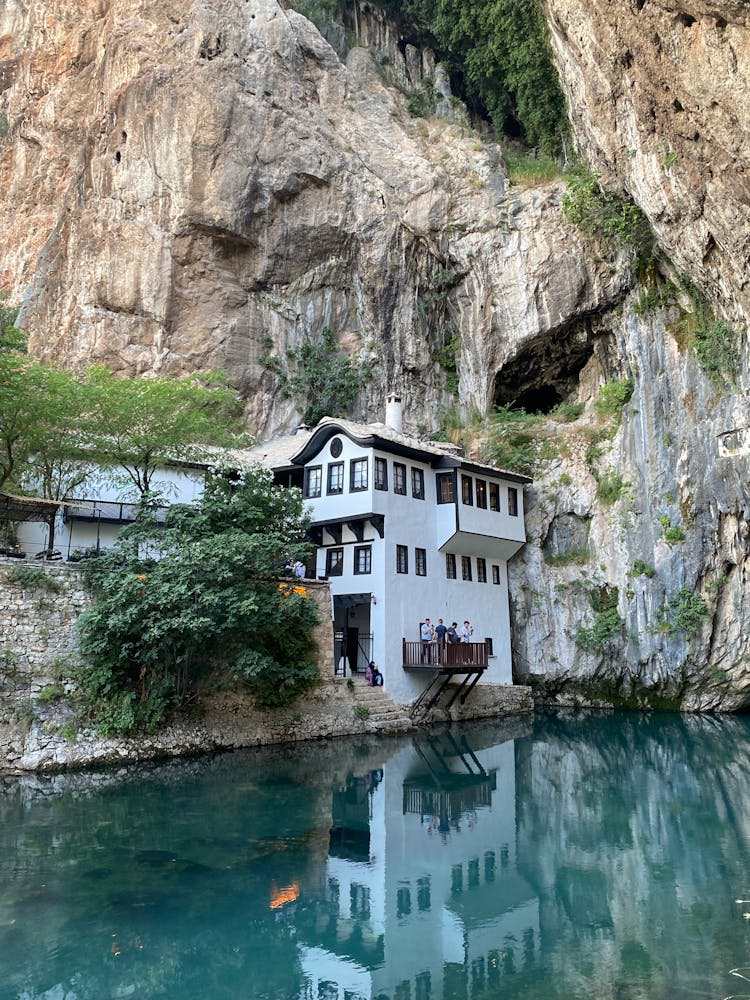 People On A Balcony Of A House Near A Rocky Mountain