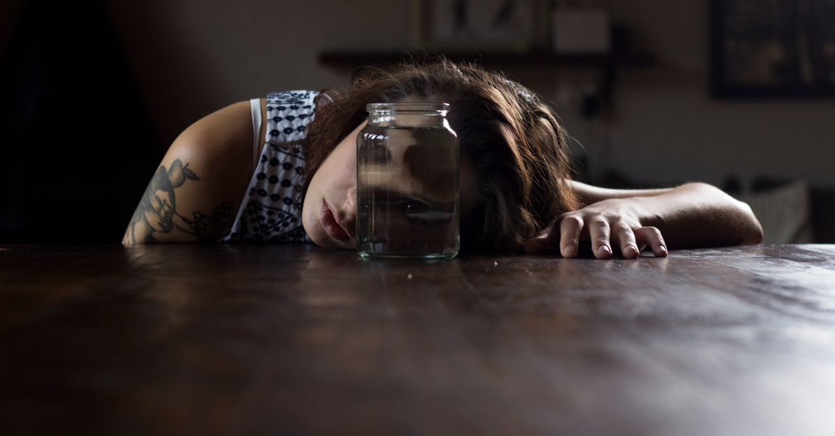 person holding a mason jar of green liquid looking confused